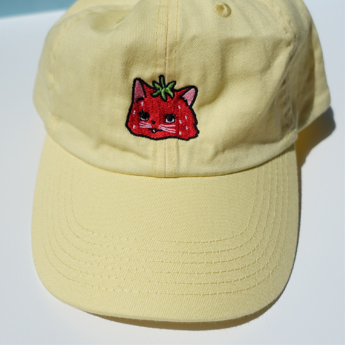 Embroidered dad hat featuring a cute strawberry cat design on yellow fabric
